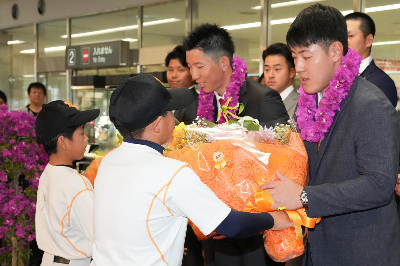 宮崎空港に到着し、歓迎セレモニーで花束を受けとる巨人岡本和（右）と戸郷（撮影・鈴木みどり）