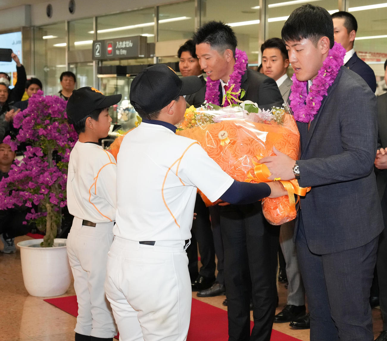 宮崎空港に到着し、歓迎セレモニーで花束を受けとる巨人岡本和（右）と戸郷（撮影・鈴木みどり）