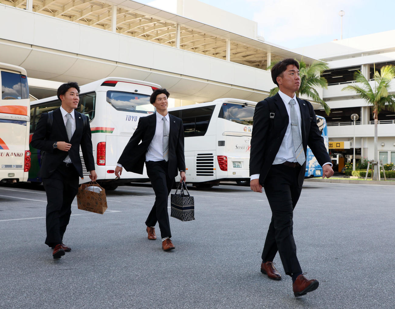 空路で沖縄へ移動しバスへ向かう富田、湯浅、村上（撮影・加藤哉）