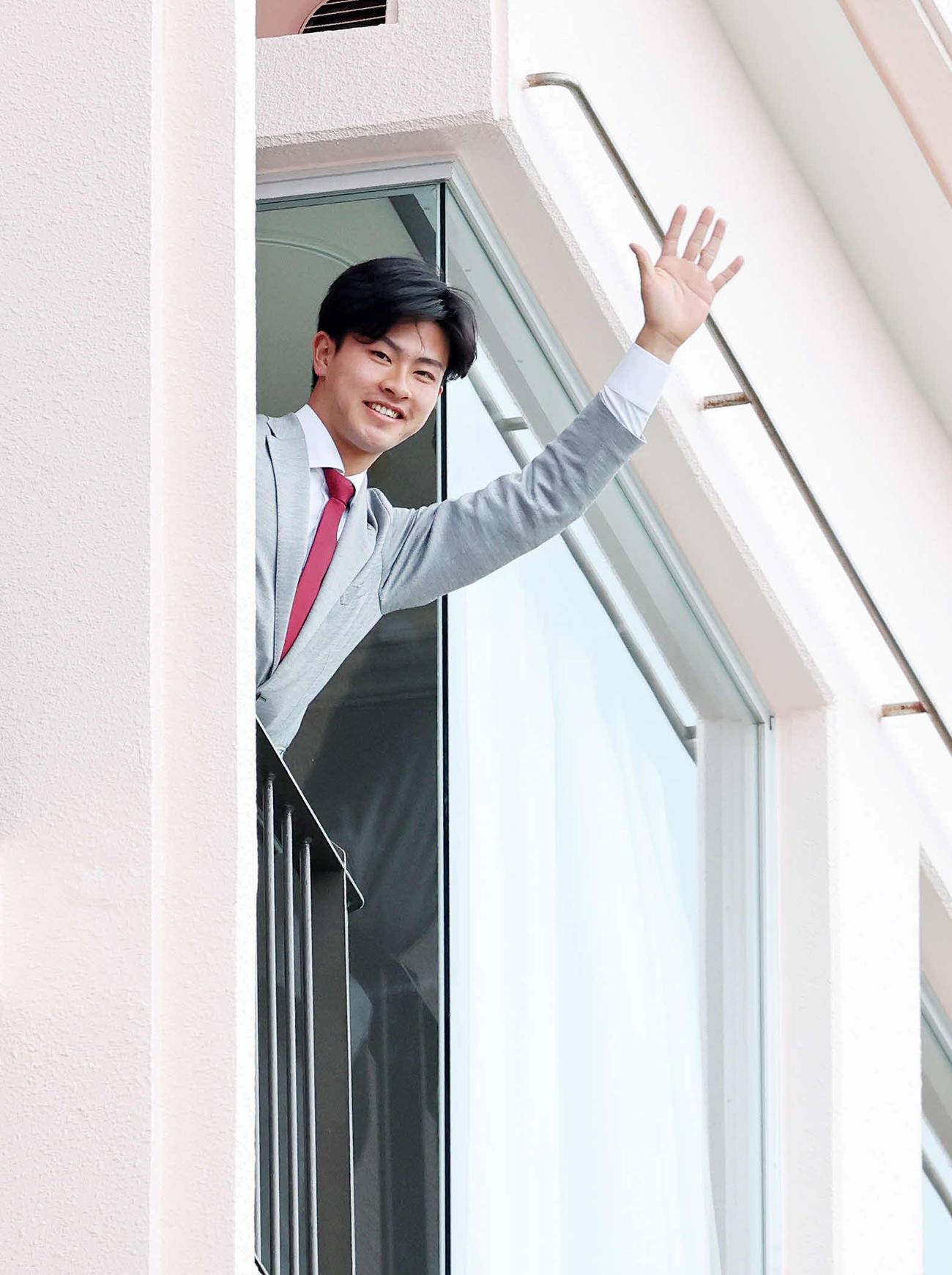 宿舎の自室テラスで手を振る楽天古謝（撮影・鈴木正人）