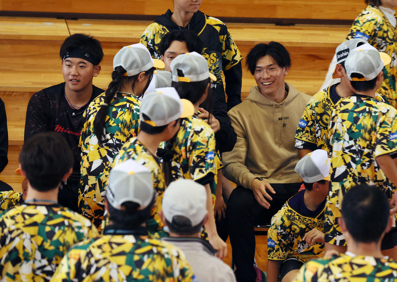 うるま市の川崎小学校を訪れ子供たちと笑顔で交流する湯浅。左は門別、中央は小幡（撮影・加藤哉）