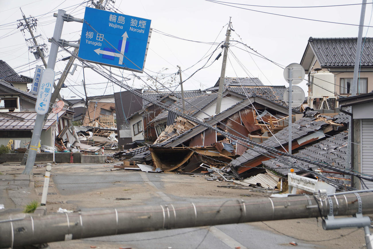 石川県珠洲市は地震の影響で電柱が倒れ、倒壊した家屋が手付かずのまま道をふさいでいた＝2024年1月20日