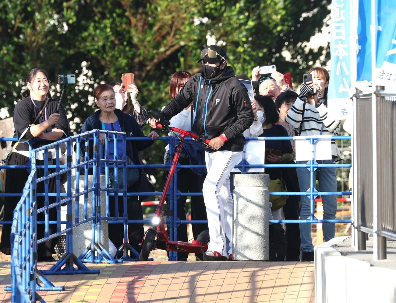 キックボードに乗って球場入りする日本ハム新庄監督（撮影・黒川智章）