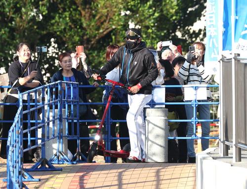 キックボードに乗って球場入りする日本ハム新庄監督（撮影・黒川智章）