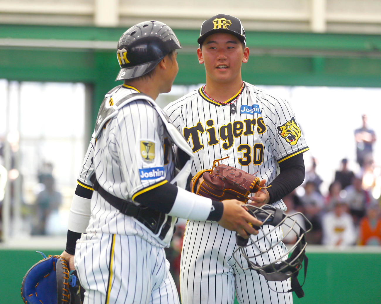 ブルペンで投球を終えた阪神門別（右）は捕手梅野のアドバイスを聞く（撮影・上山淳一）