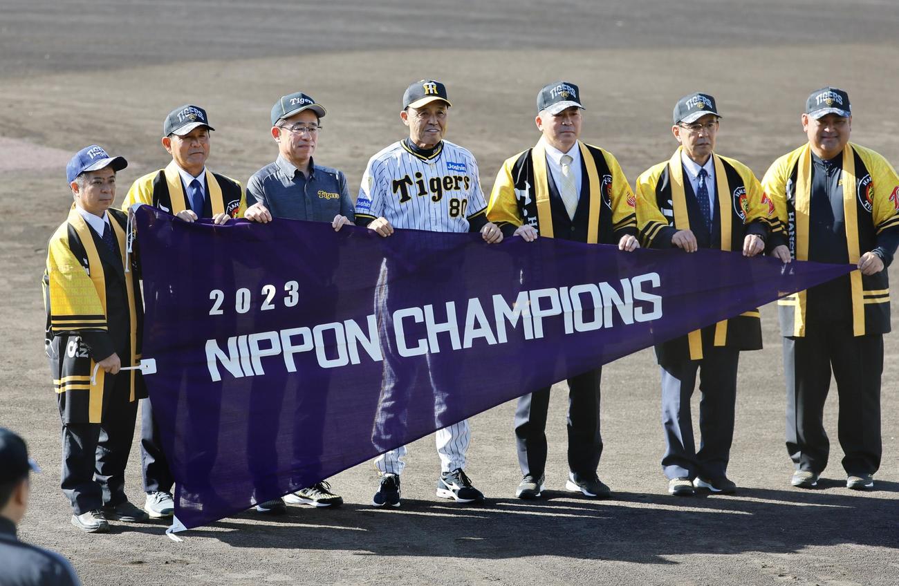 阪神春季キャンプ　セレモニーでチャンピオンブラックのレプリカを贈り、記念写真に納まる岡田彰布監督（中央）（撮影・藤尾明華）