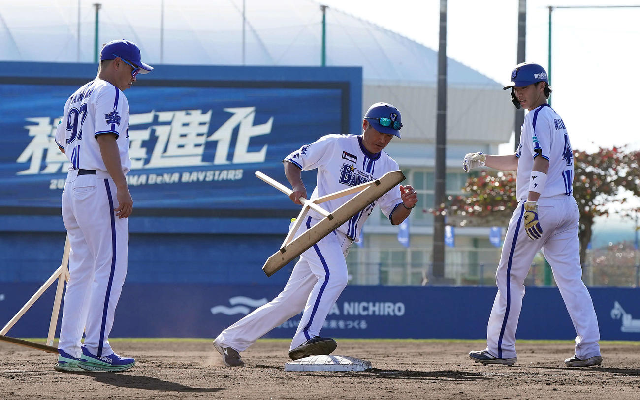 度会（右）にトンボを手にしたまま走塁の指導をするDeNA石井コーチ。左は田中コーチ（撮影・たえ見朱実）