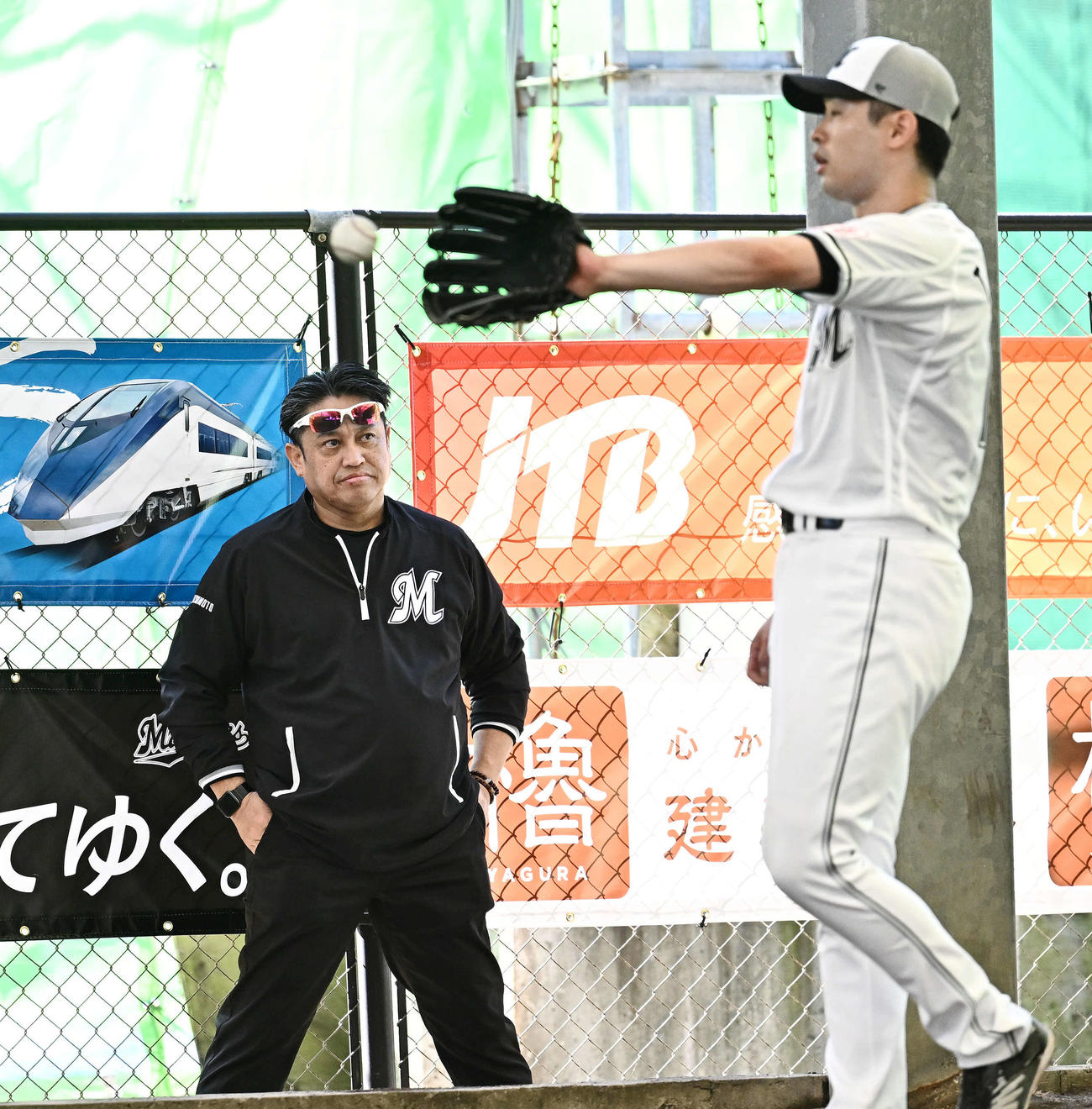ブルペンを視察するロッテ松本球団本部長。手前は種市（撮影・滝沢徹郎）