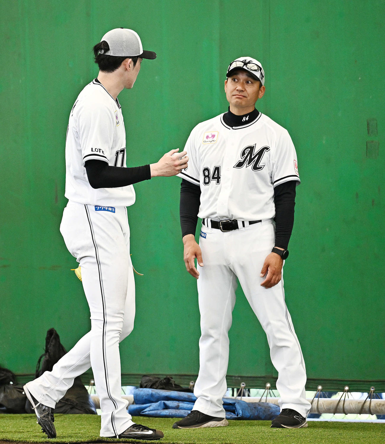 ブルペンの投球練習を終えたロッテ佐々木（左）と話す黒木投手コーチ（撮影・滝沢徹郎）