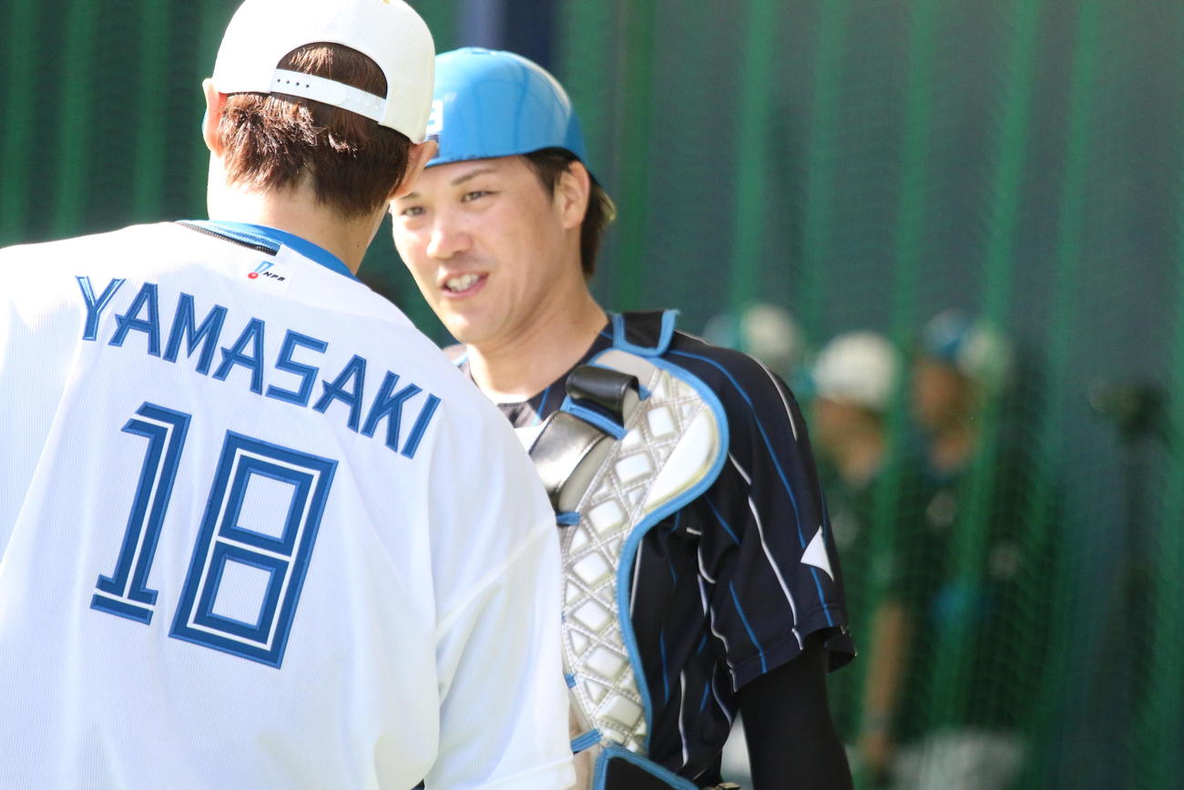 キャンプ初ブルペンに入った日本ハム山崎（左）と投球を受けた伏見（撮影・木下大輔）