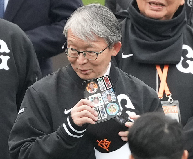 ナインの前で阿部監督のシールを手にする巨人山口オーナー（撮影・鈴木みどり）
