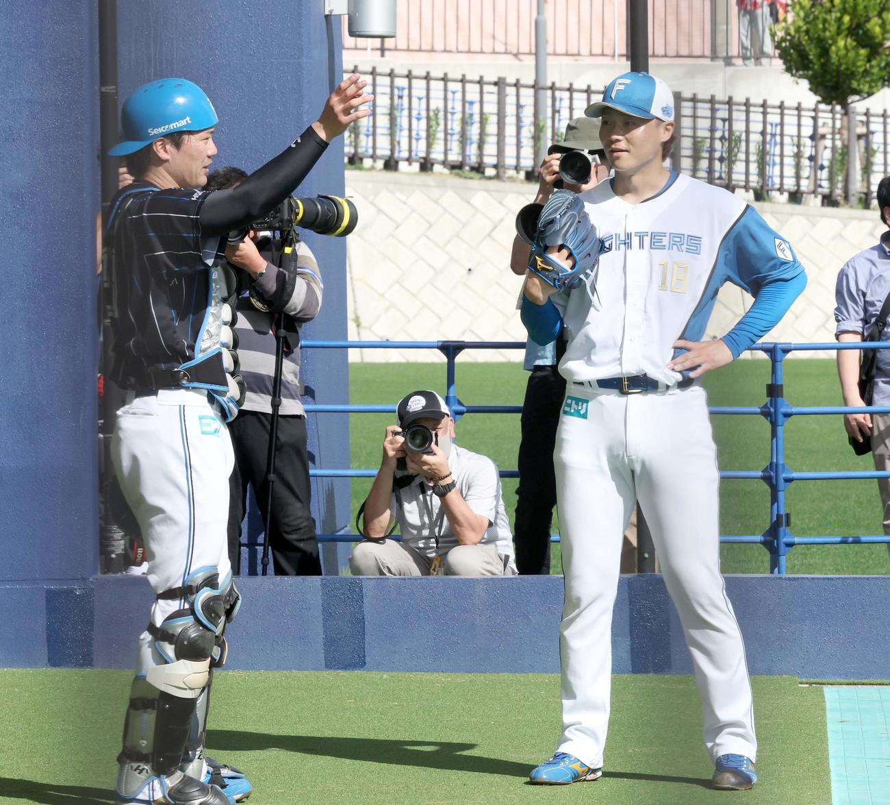 ブルペンで投球後、伏見（左）と話す日本ハム山崎（撮影・黒川智章）