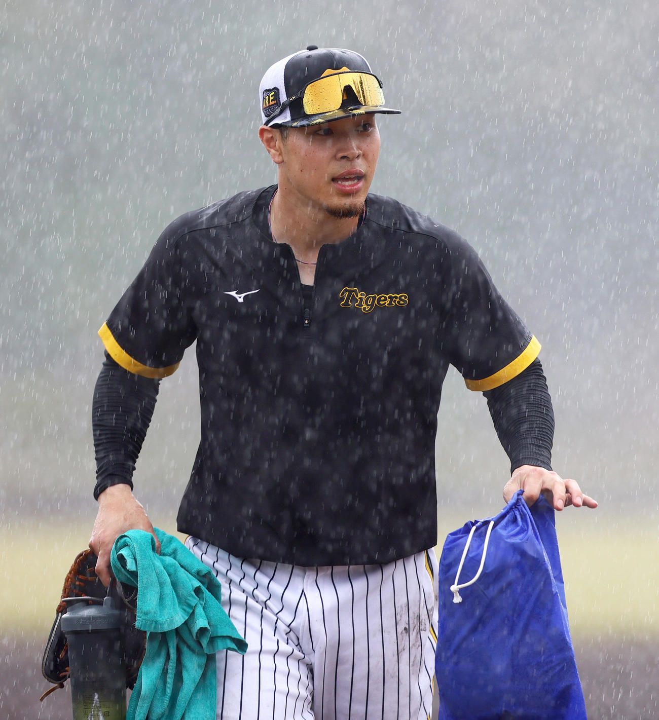 突然の雨に見舞われ室内へ移動する阪神佐藤輝（撮影・上山淳一）