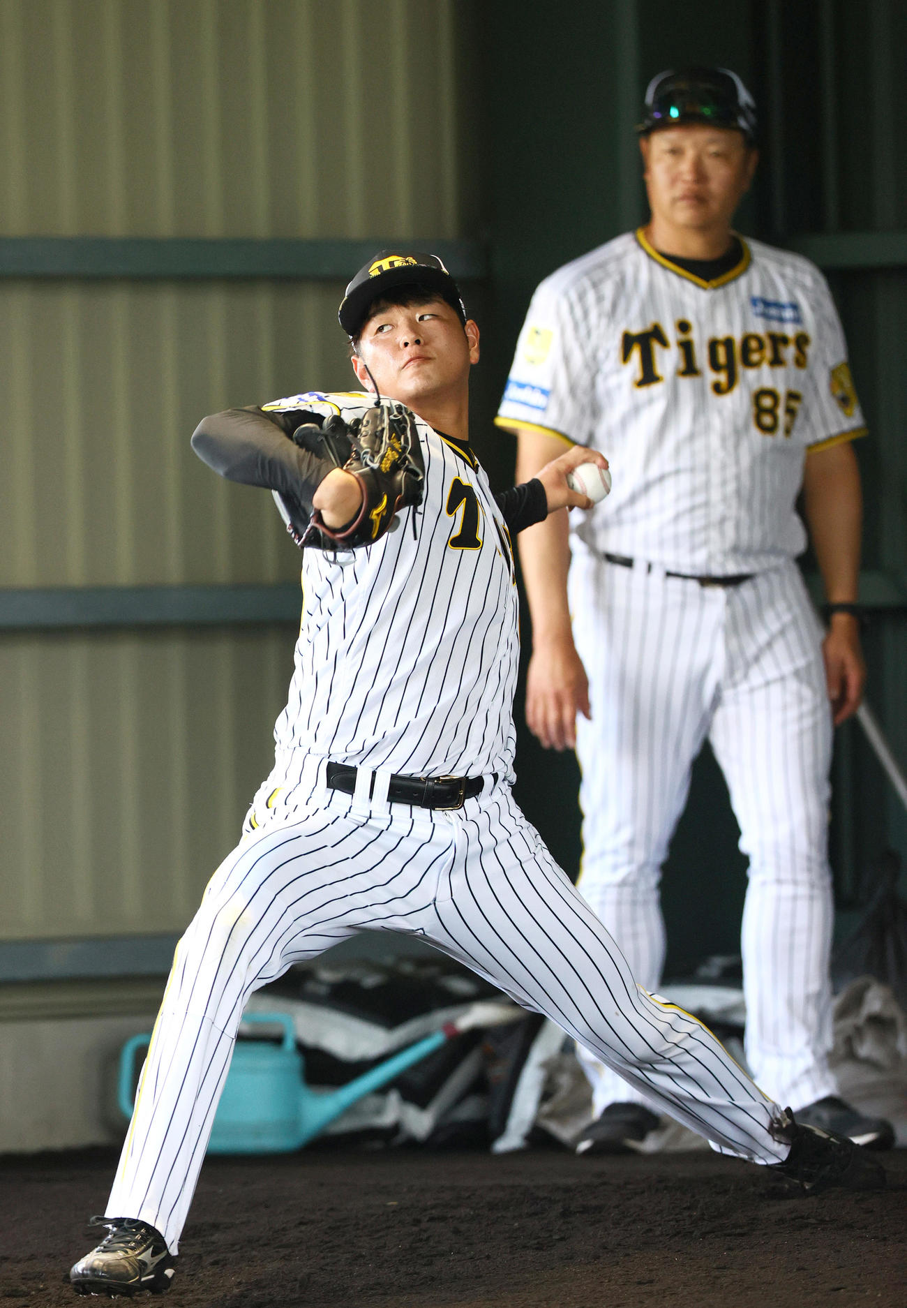 ブルペンで投球する阪神高橋。奥は福原2軍投手コーチ（撮影・上山淳一）