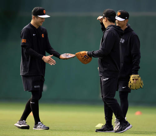早出練習で、ノック用の平らなグラブを見せ合う巨人泉口（左）と門脇。奥は吉川（撮影・浅見桂子）