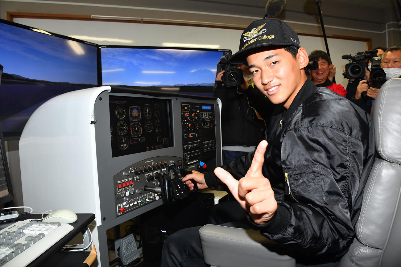 キャンプ休日の新人体験で飛行機のシミュレーター操縦体験を行い、VIVAポーズを決めるソフトバンク前田悠（撮影・岩下翔太）