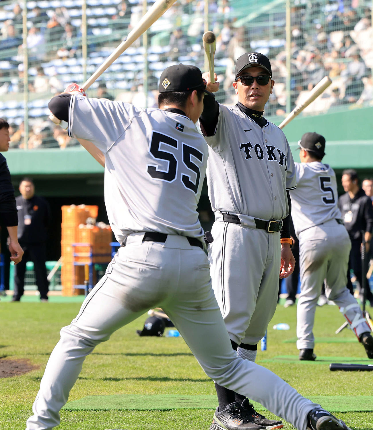 巨人秋広（左）のティー打撃中、腰が浮かないように、バットで頭を押さえて指導する阿部監督（撮影・浅見桂子）