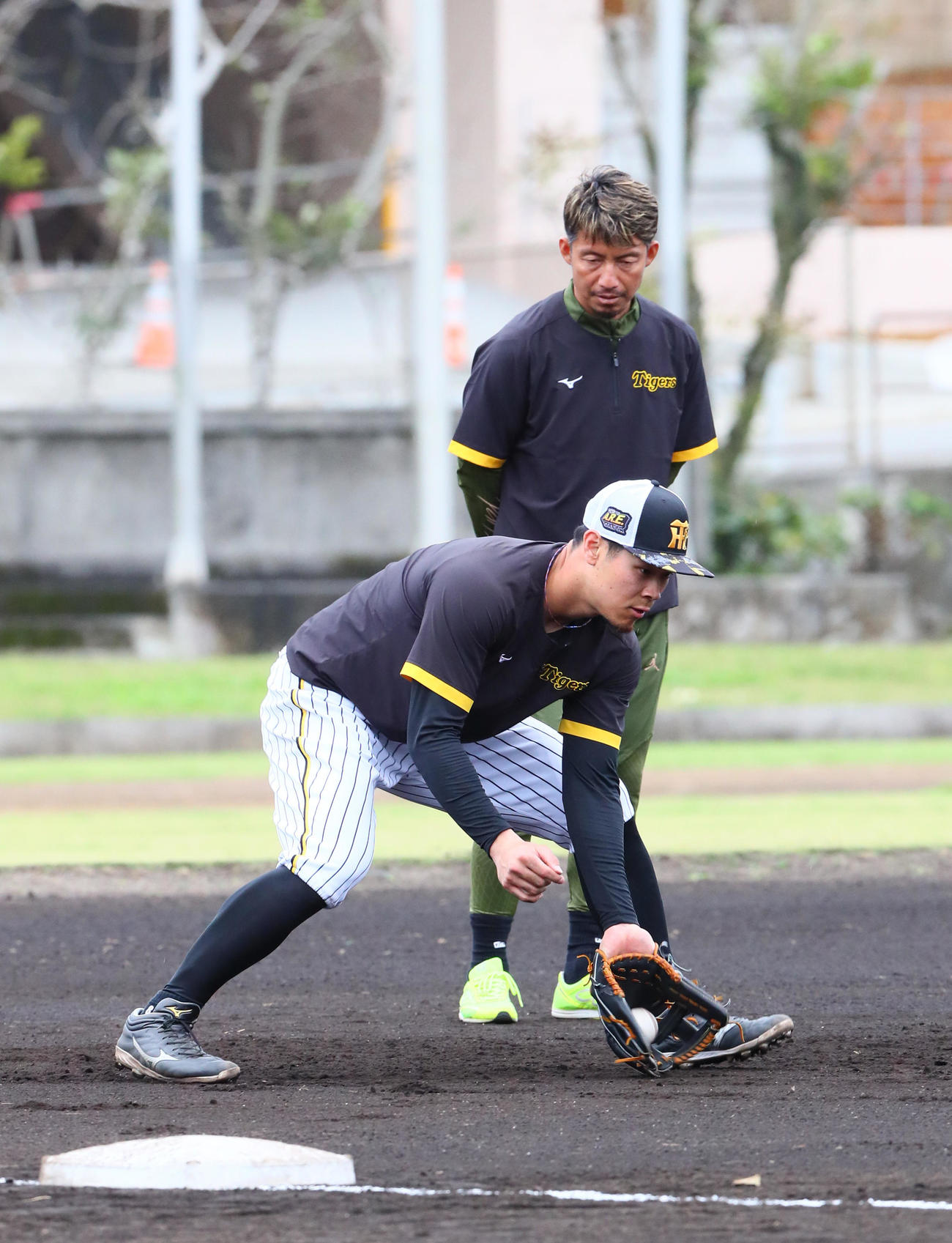 阪神佐藤輝（手前）は鳥谷臨時コーチから守備の指導を受ける（撮影・上山淳一）