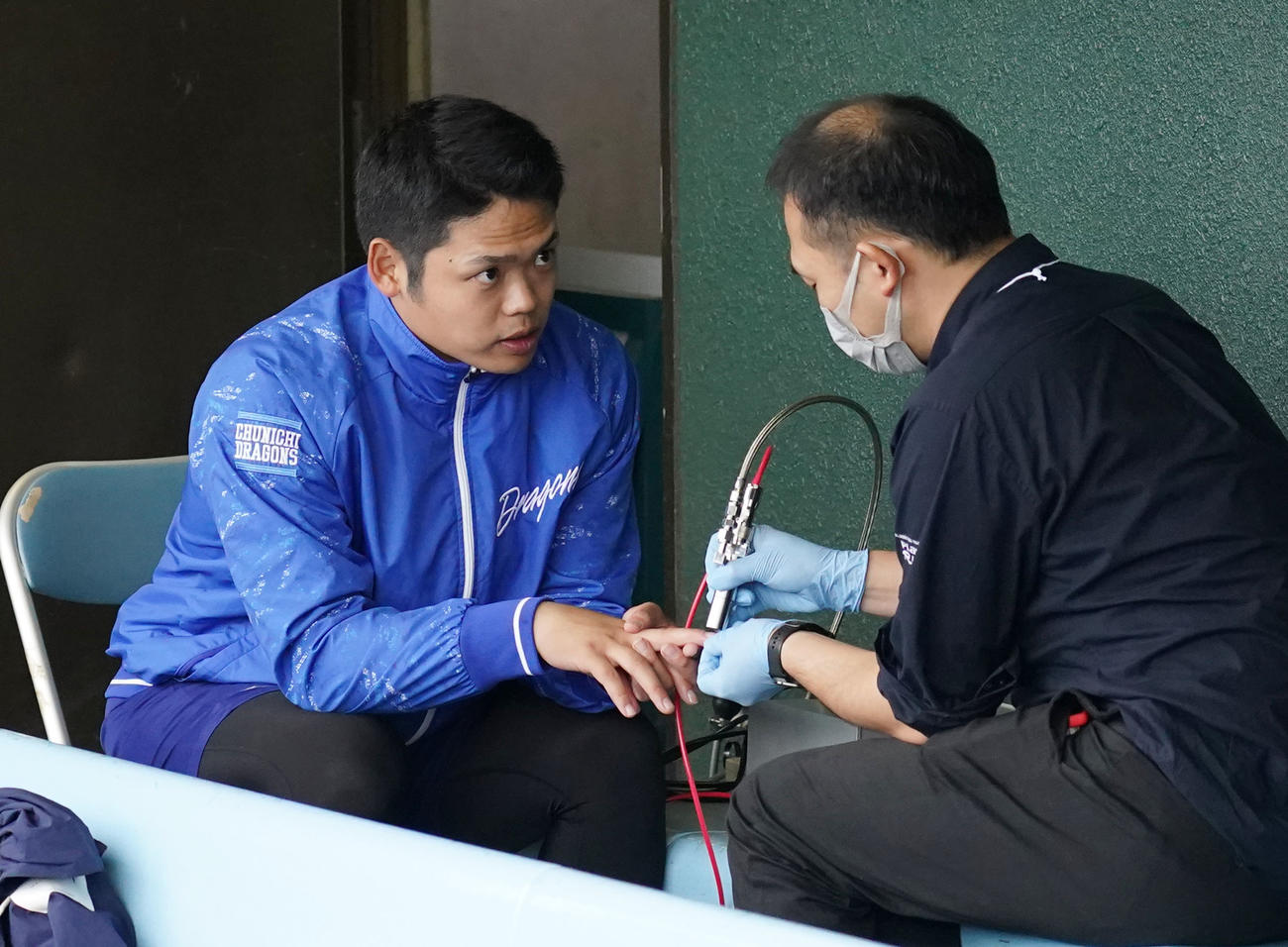 練習後、右手中指の爪の手入れを受ける中日根尾（左）（撮影・森本幸一）