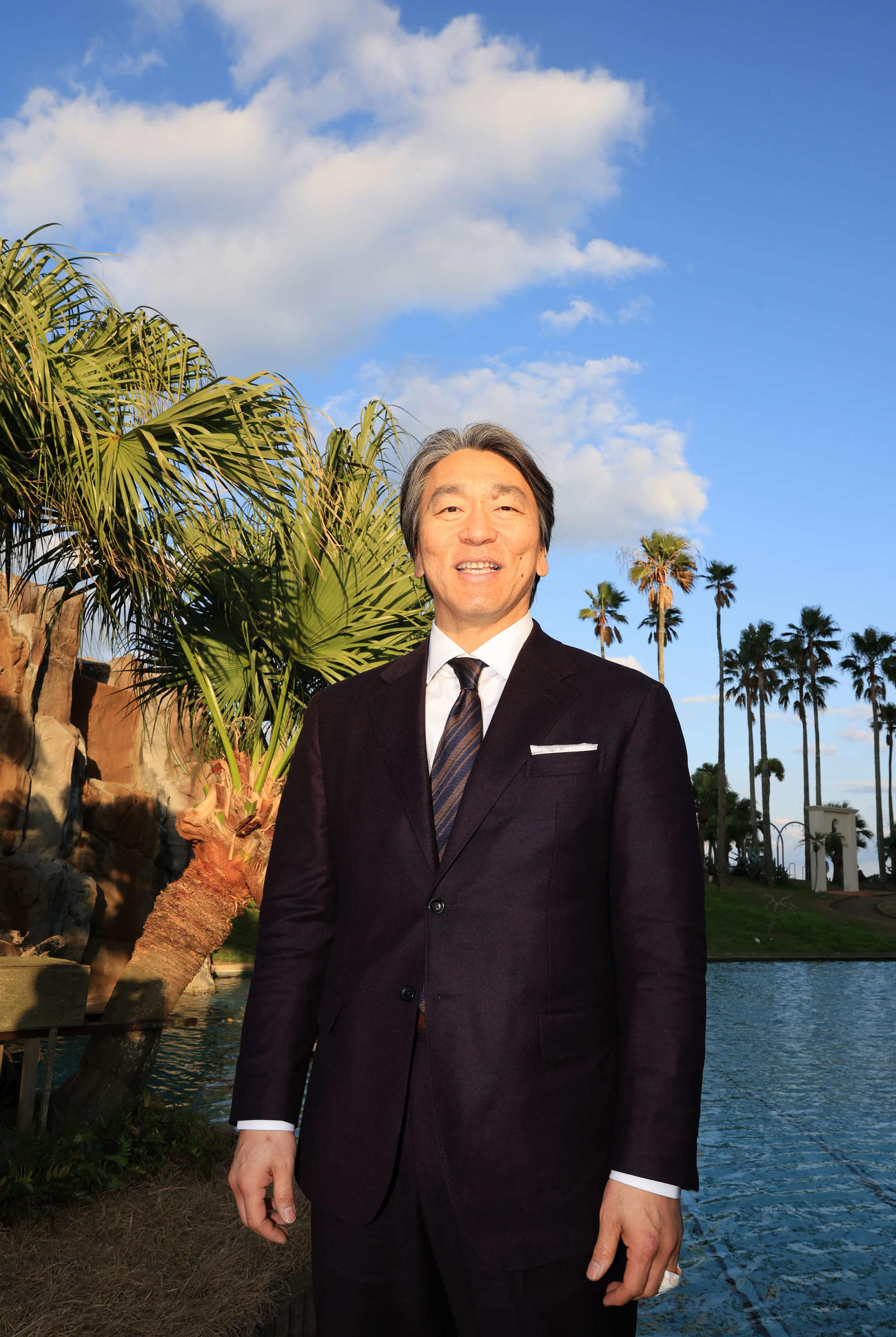 巨人の臨時コーチを務めるため宮崎入りした松井秀喜氏は、宿舎でヤシの木を背に懐かしそうに笑顔を見せる（撮影・浅見桂子）