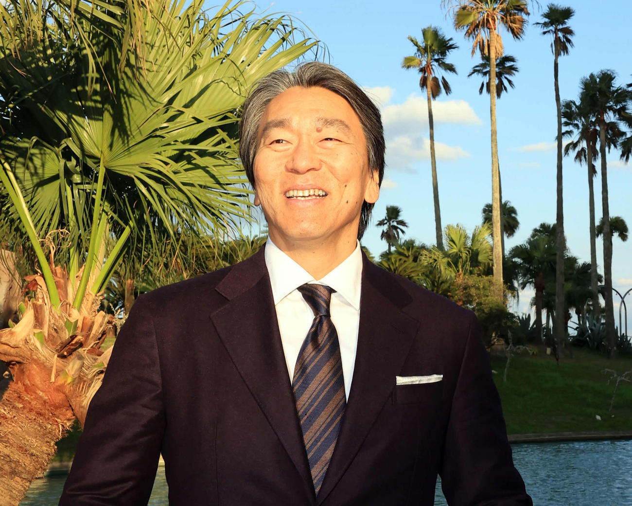 巨人の臨時コーチを務めるため宮崎入りした松井秀喜氏は、宿舎でヤシの木を背に懐かしそうに笑顔を見せる（撮影・浅見桂子）