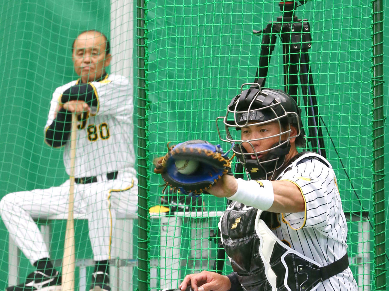 2日、ブルペンで捕球する阪神梅野（右）を見つめる岡田監督