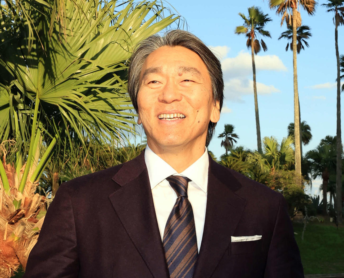 巨人の臨時コーチを務めるため宮崎入りした松井秀喜氏は、宿舎でヤシの木を背に懐かしそうに笑顔を見せる（撮影・浅見桂子）