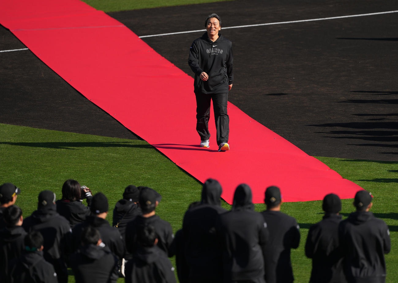 レッドカーペットを笑顔で歩き、選手たちの方へ向かう松井臨時コーチ（撮影・鈴木みどり）