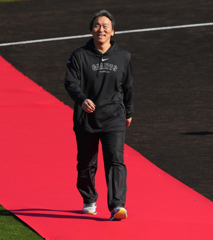 レッドカーペットを笑顔で歩き、選手たちの方へ向かう松井臨時コーチ（撮影・鈴木みどり）