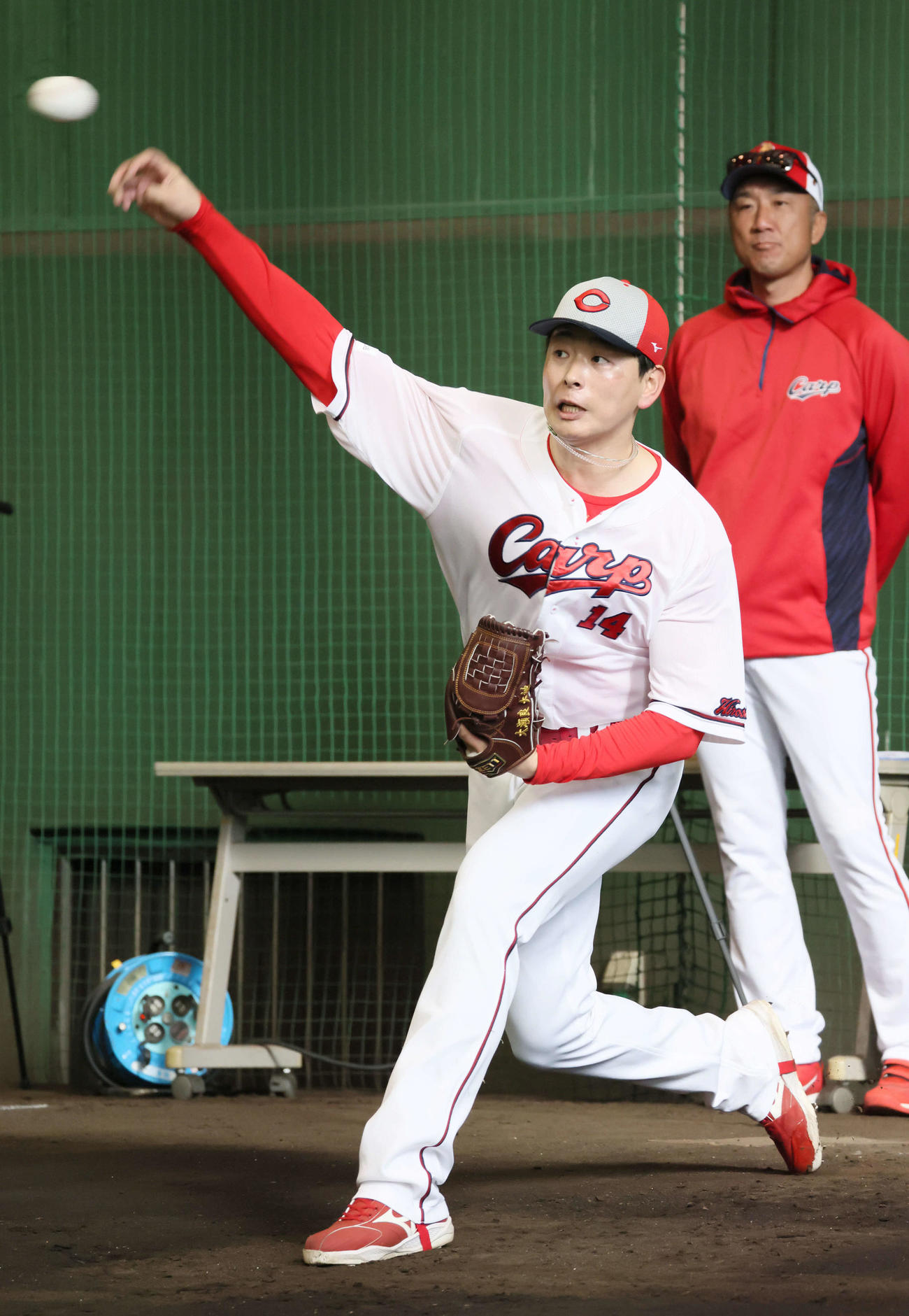 捕手を座らせて、ブルペンで投球する広島大瀬良。右は永川投手コーチ（撮影・加藤孝規）