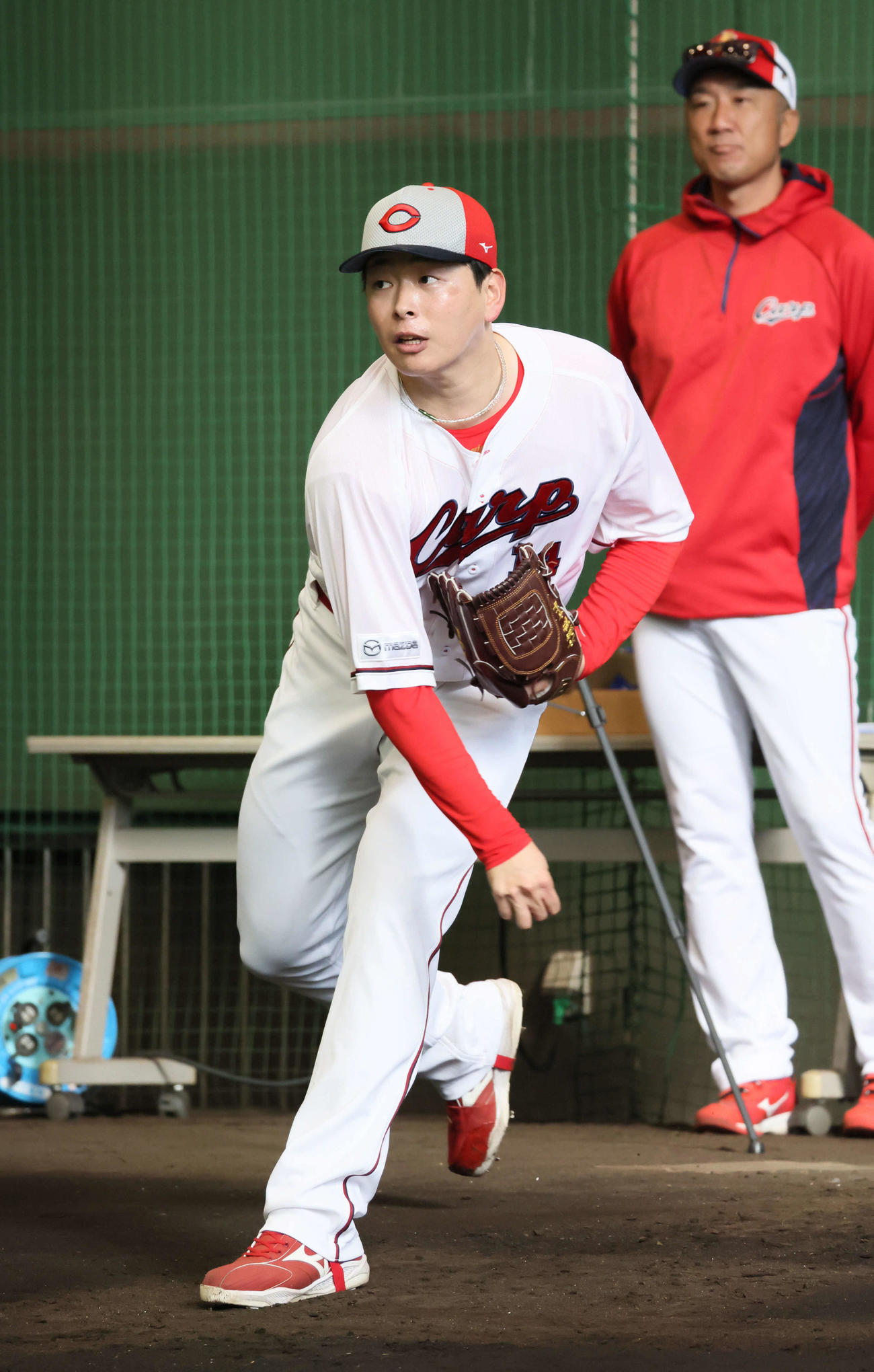 捕手を座らせて、ブルペンで投球する広島大瀬良。右は永川投手コーチ（撮影・加藤孝規）