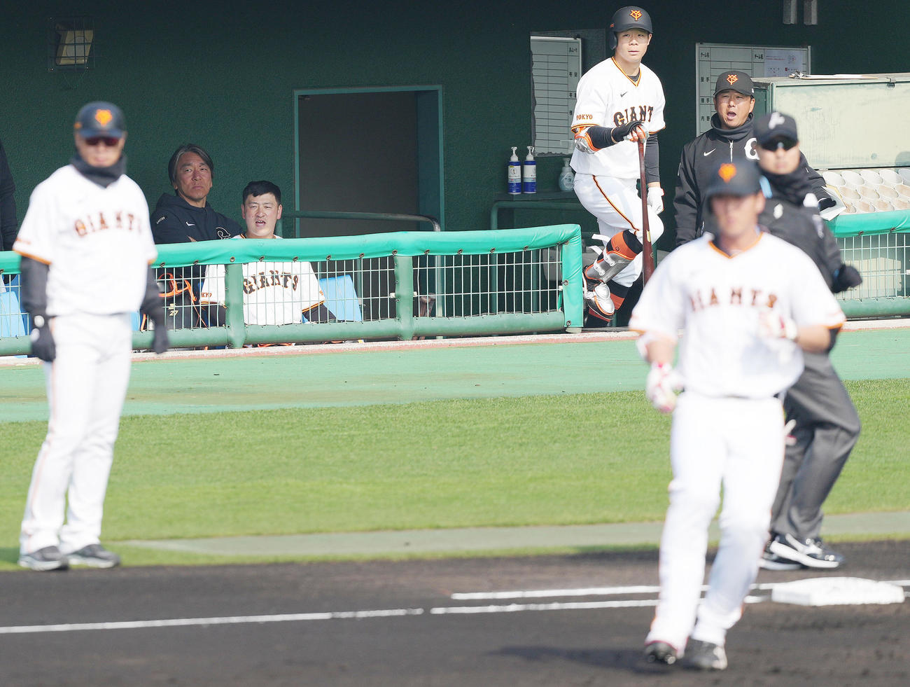 巨人紅白戦　1回裏白組2死、右前打を放った秋広（右手前）を見る松井臨時コーチ（左奥）（撮影・鈴木みどり）