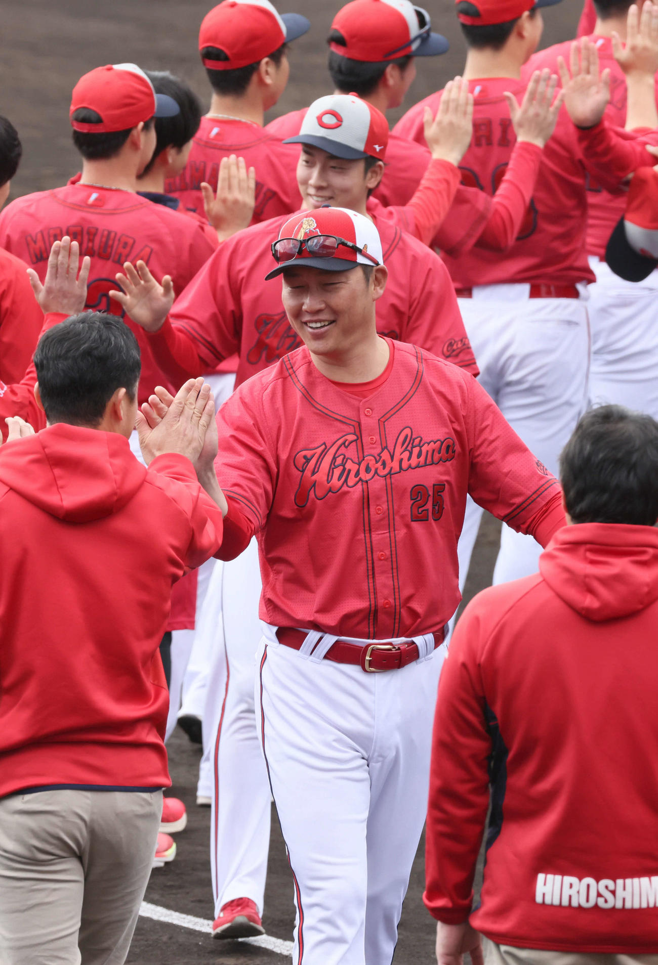 日南キャンプ打ち上げでナインらとタッチする広島新井監督（中央）。後ろはドラフト1位の常広（撮影・加藤孝規）