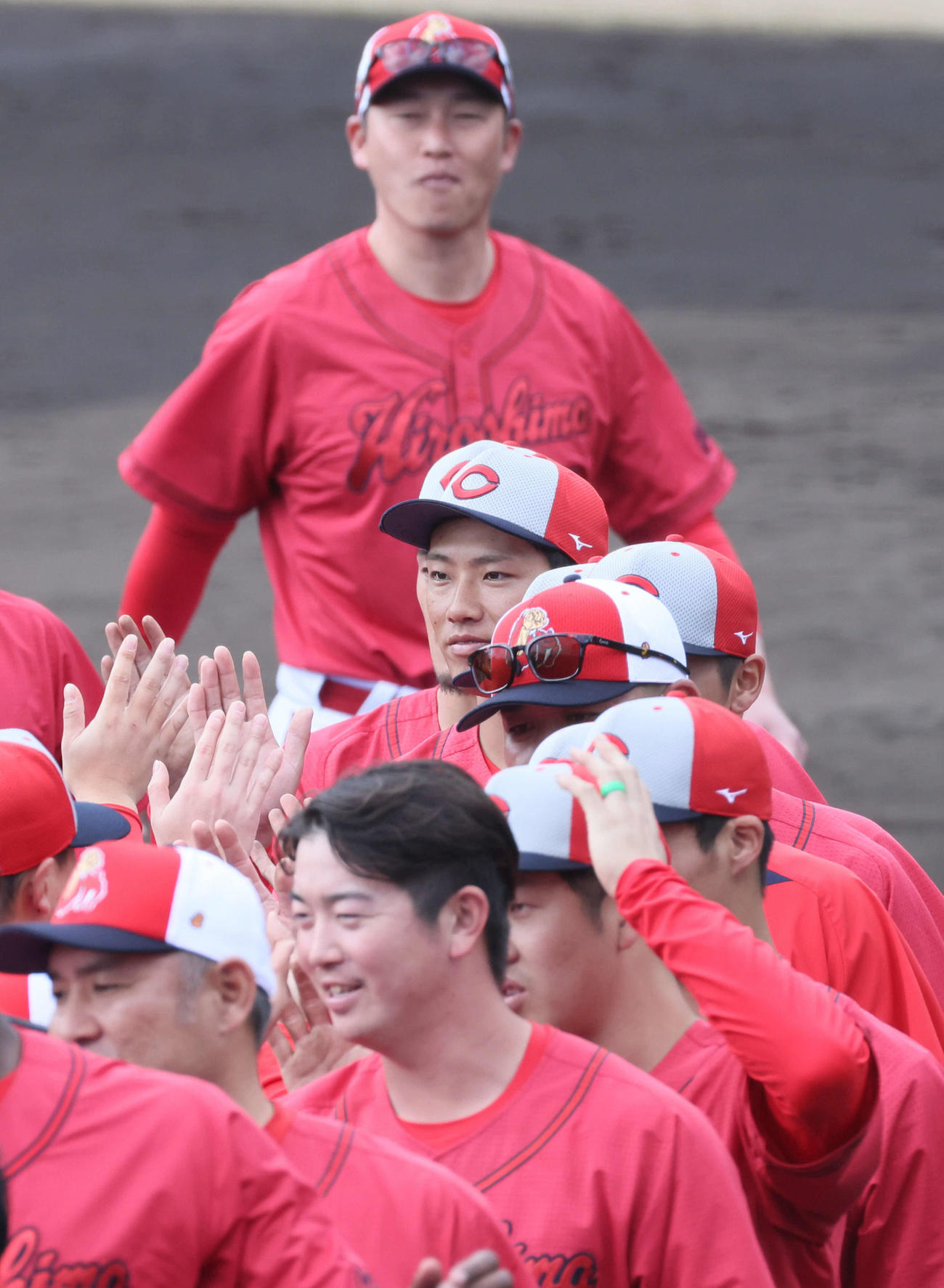日南キャンプ打ち上げでナインとタッチする広島中村奨（中央）。後ろは新井監督（撮影・加藤孝規）