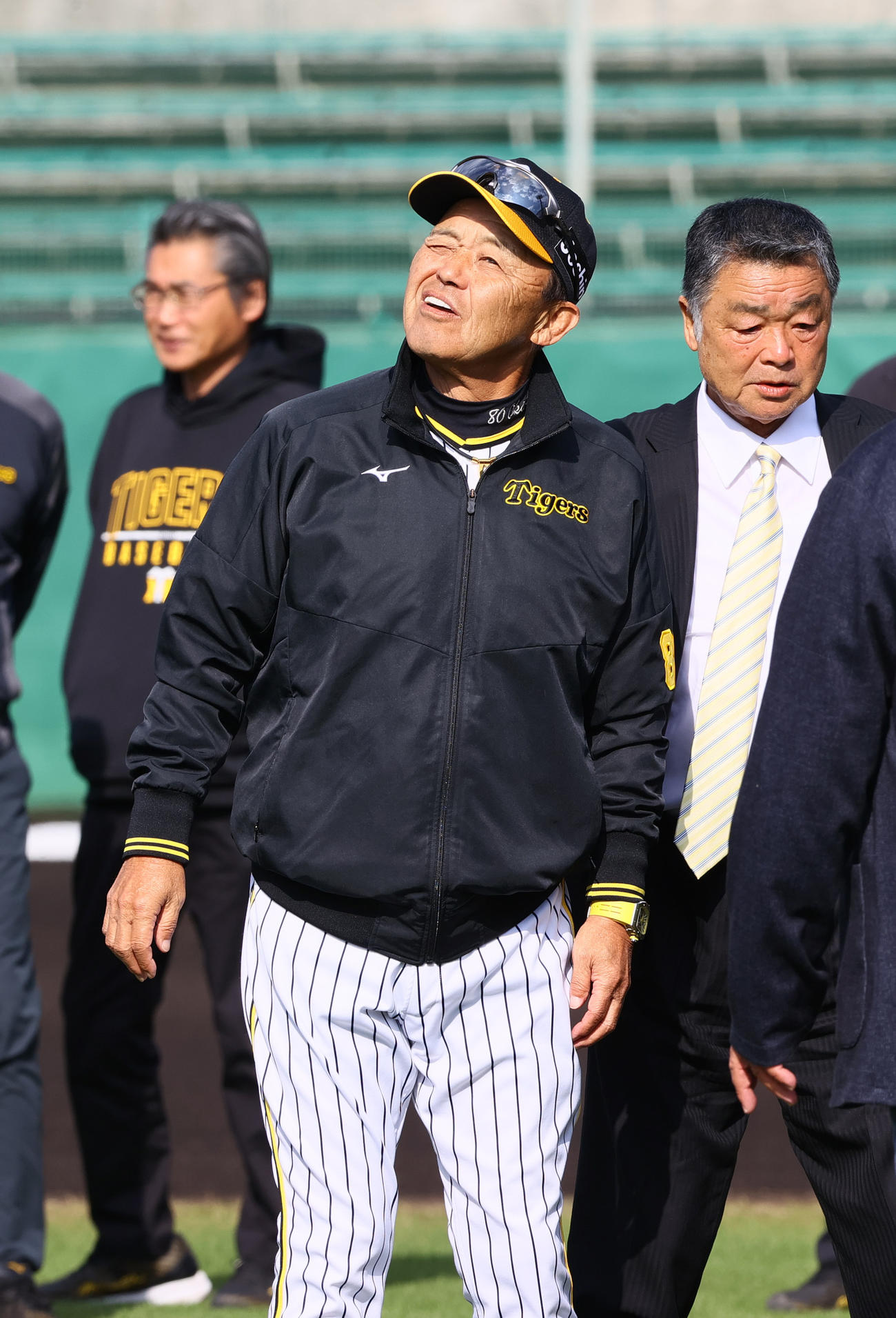 宜野座の強い日差しにまぶしそうにする阪神岡田監督。右は川藤OB会長（撮影・上山淳一）