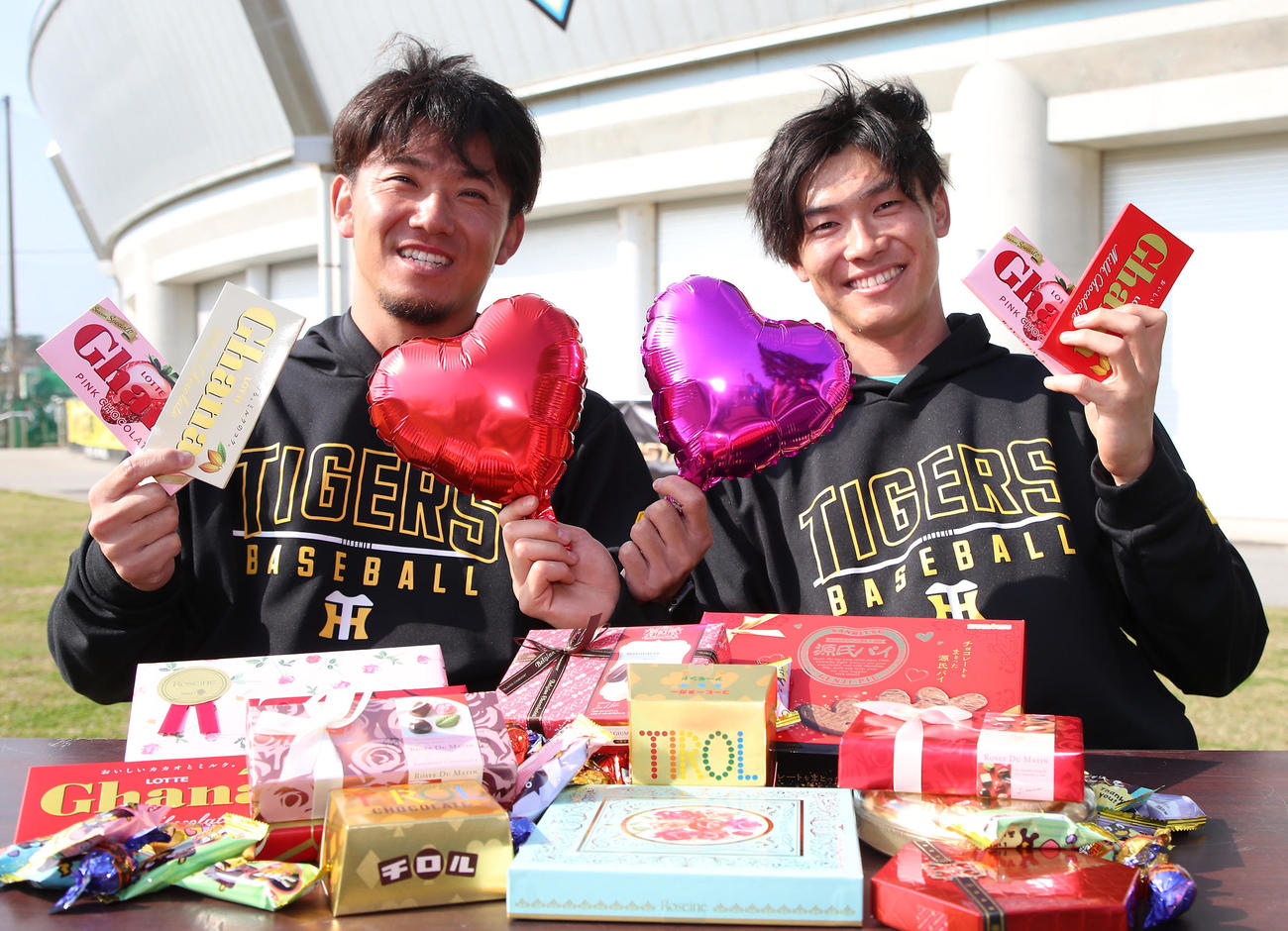 バレンタインチョコレートとハートのバルーンを手に笑顔を見せる阪神伊藤将（左）と湯浅（撮影・上山淳一）