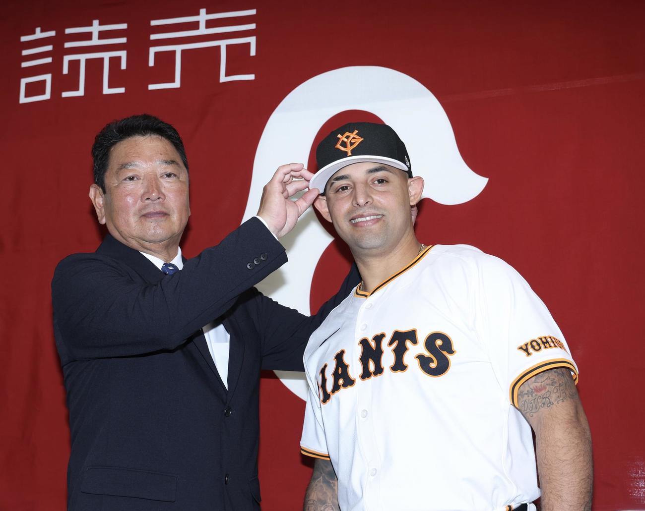 入団会見で、吉村編成本部長に（左）に帽子を被せてもらう巨人オドーア（撮影・河田真司）
