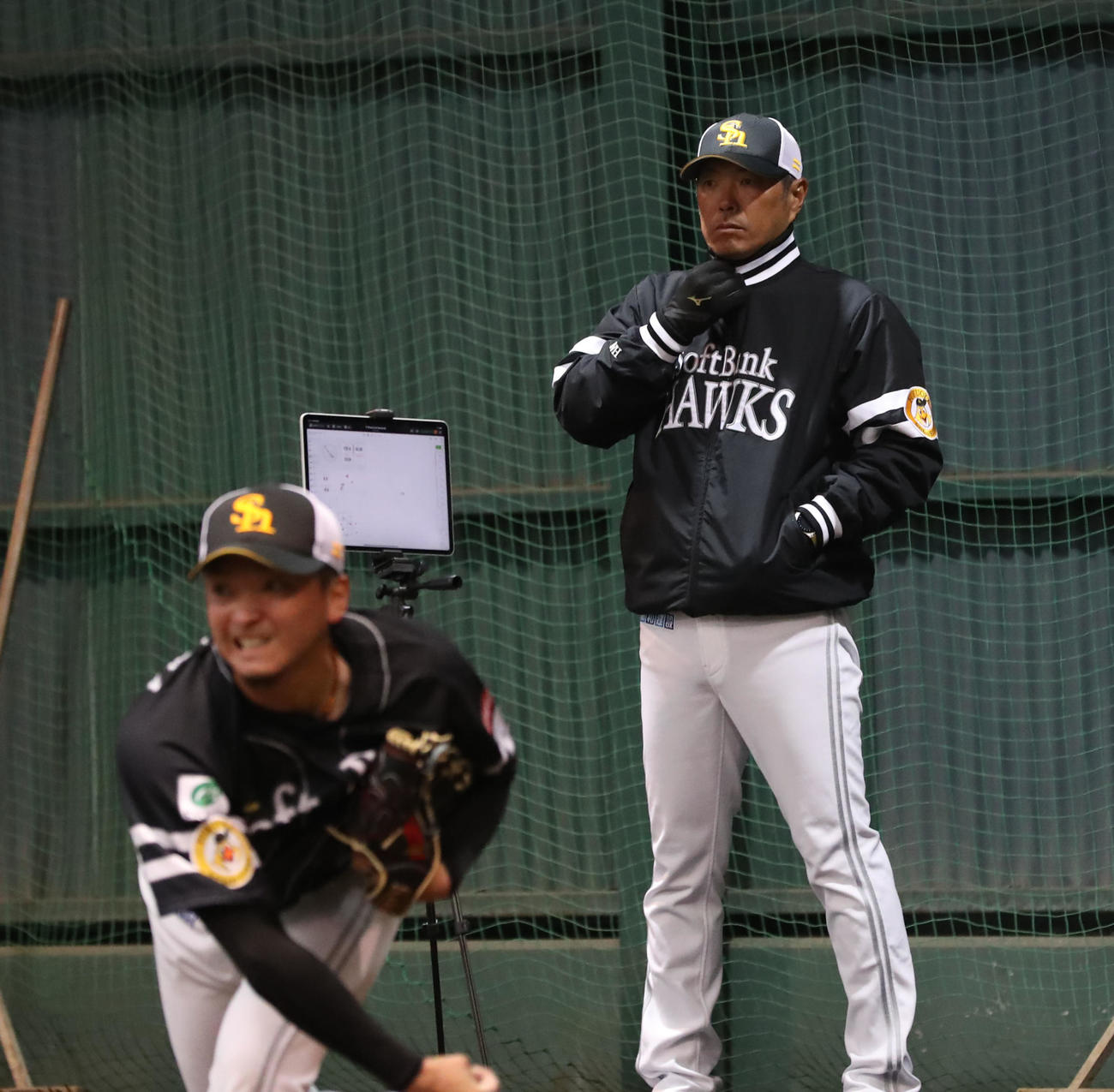 ブルペン投球するソフトバンク東浜巨を見守る小久保監督（奥）（撮影・冨田成美）