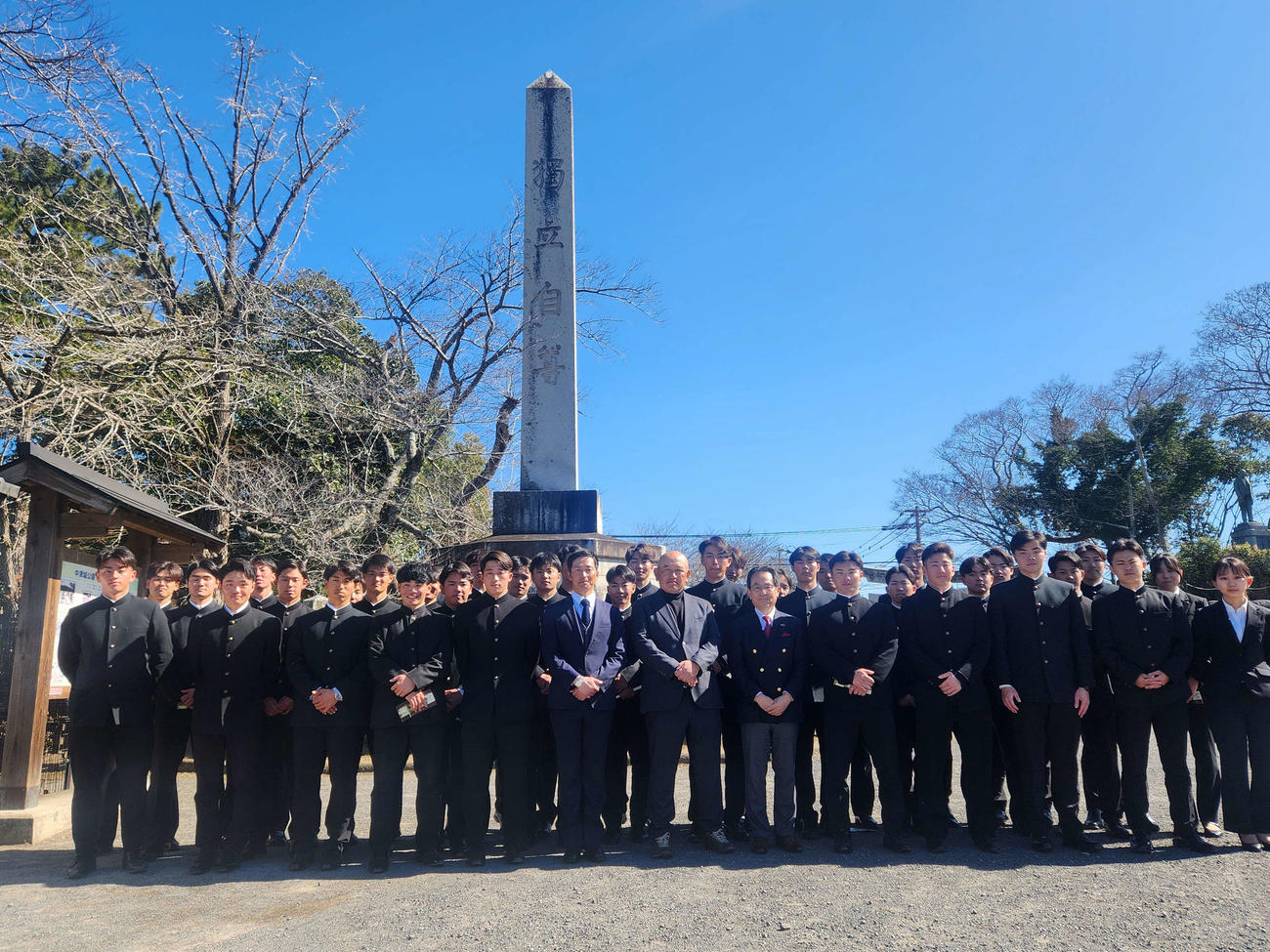 中津城公園にある「独立自尊碑」の前で記念撮影に写る慶大の選手とスタッフ（撮影・保坂淑子）