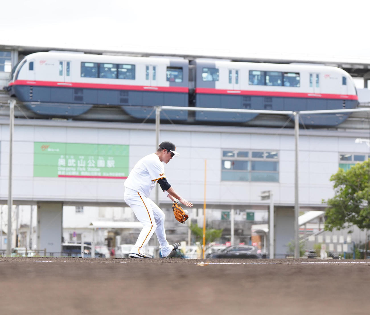 サブグラウンドでノックを受ける巨人坂本。後方は沖縄都市モノレールの「ゆいレール」（撮影・江口和貴）