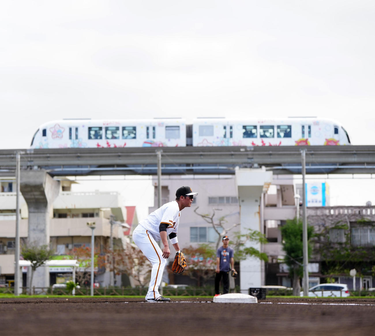 サブグラウンドでノックを受ける巨人坂本。後方は沖縄都市モノレールの「ゆいレール」（撮影・江口和貴）