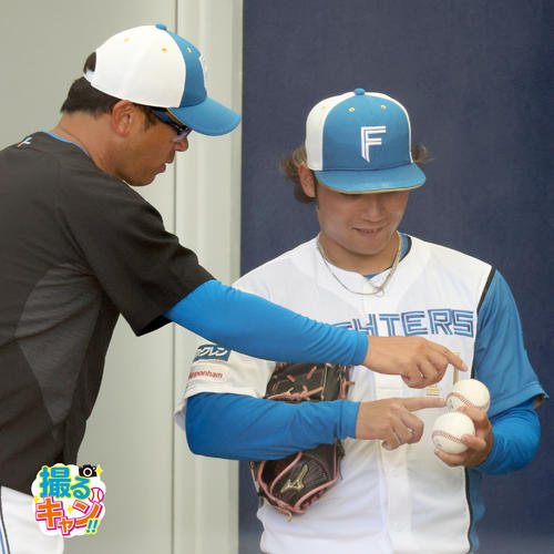 ブルペンでボールを見つめる日本ハム建山コーチ(左)と伊藤(撮影・佐藤翔太)
