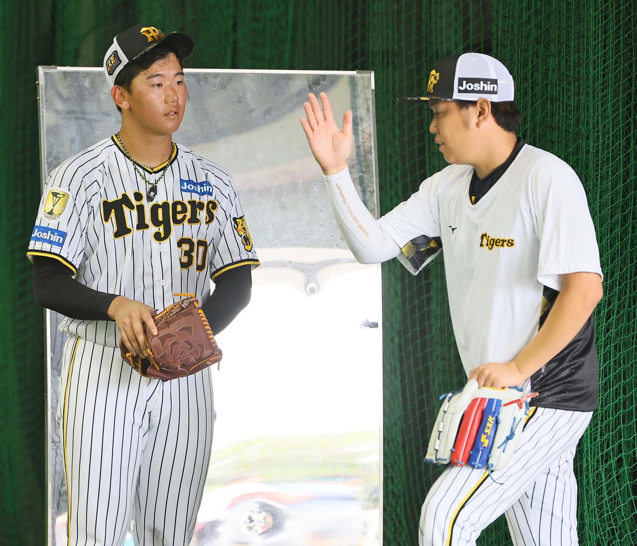 西勇輝（右）からアドバイスを受ける門別（撮影・上田博志）