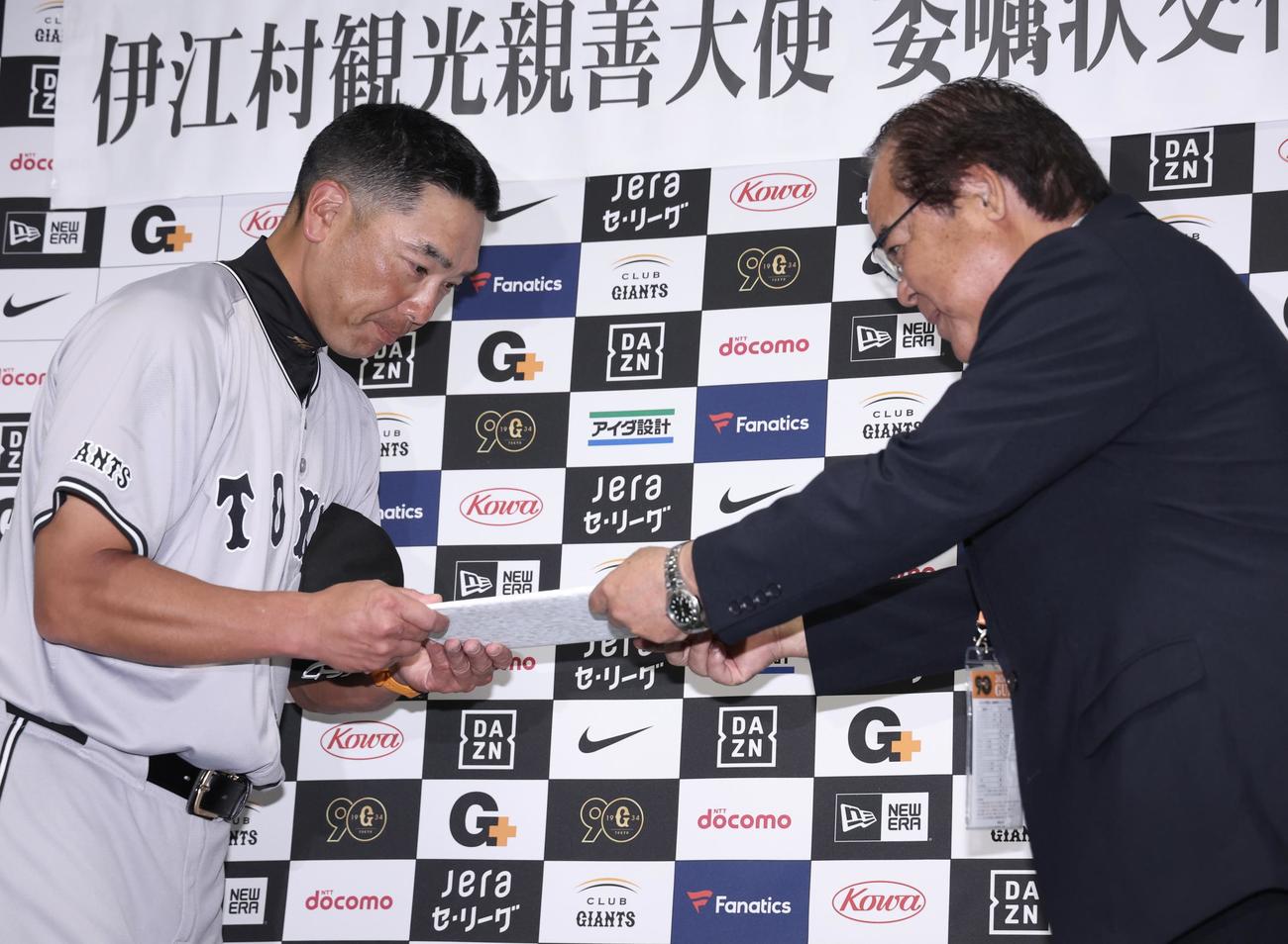 伊江村観光親善大使の巨人阿部監督（左）は、名城村長から委嘱状を受け取る（撮影・河田真司）
