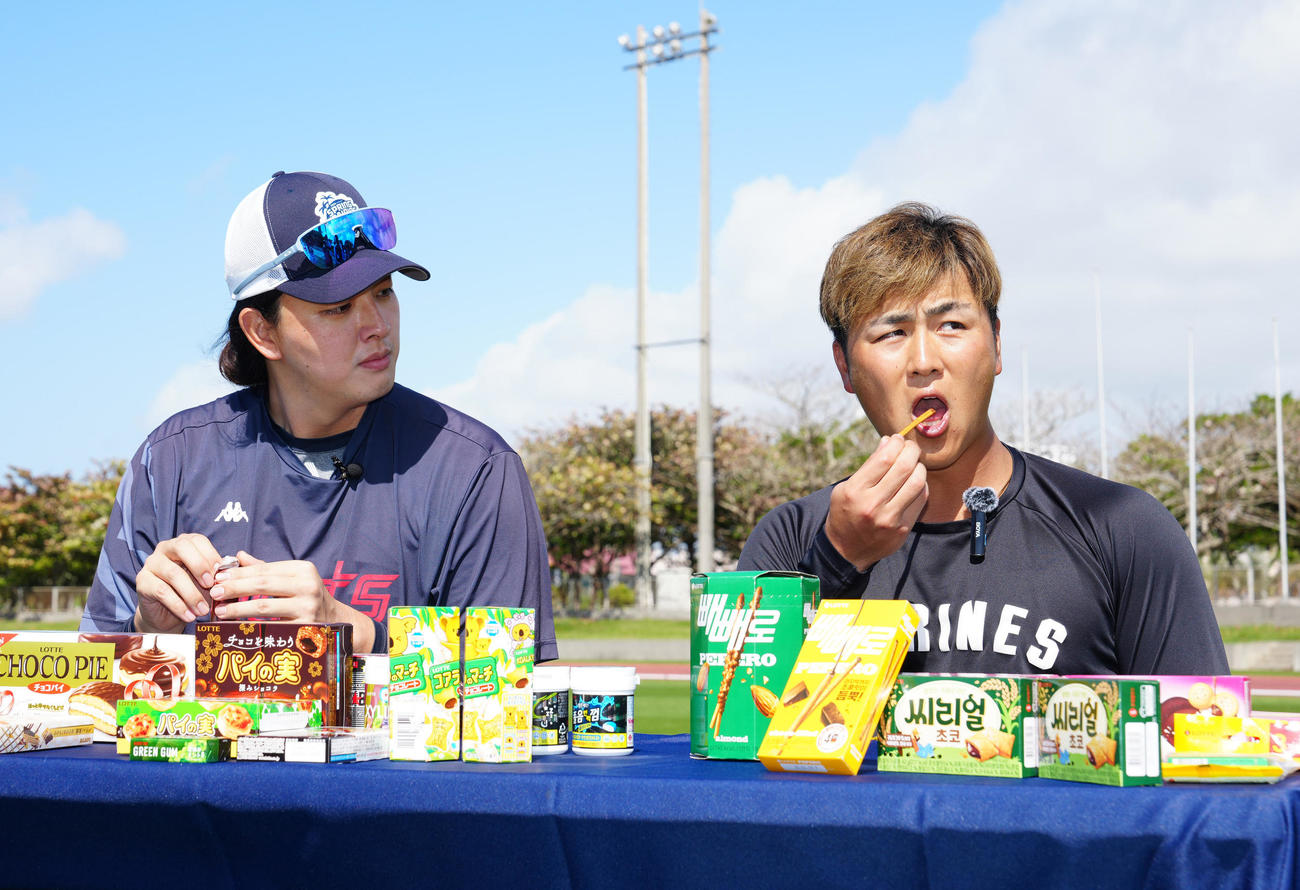 お菓子を食べ比べするロッテ山口（右）と韓国ロッテの金元中（撮影・江口和貴）