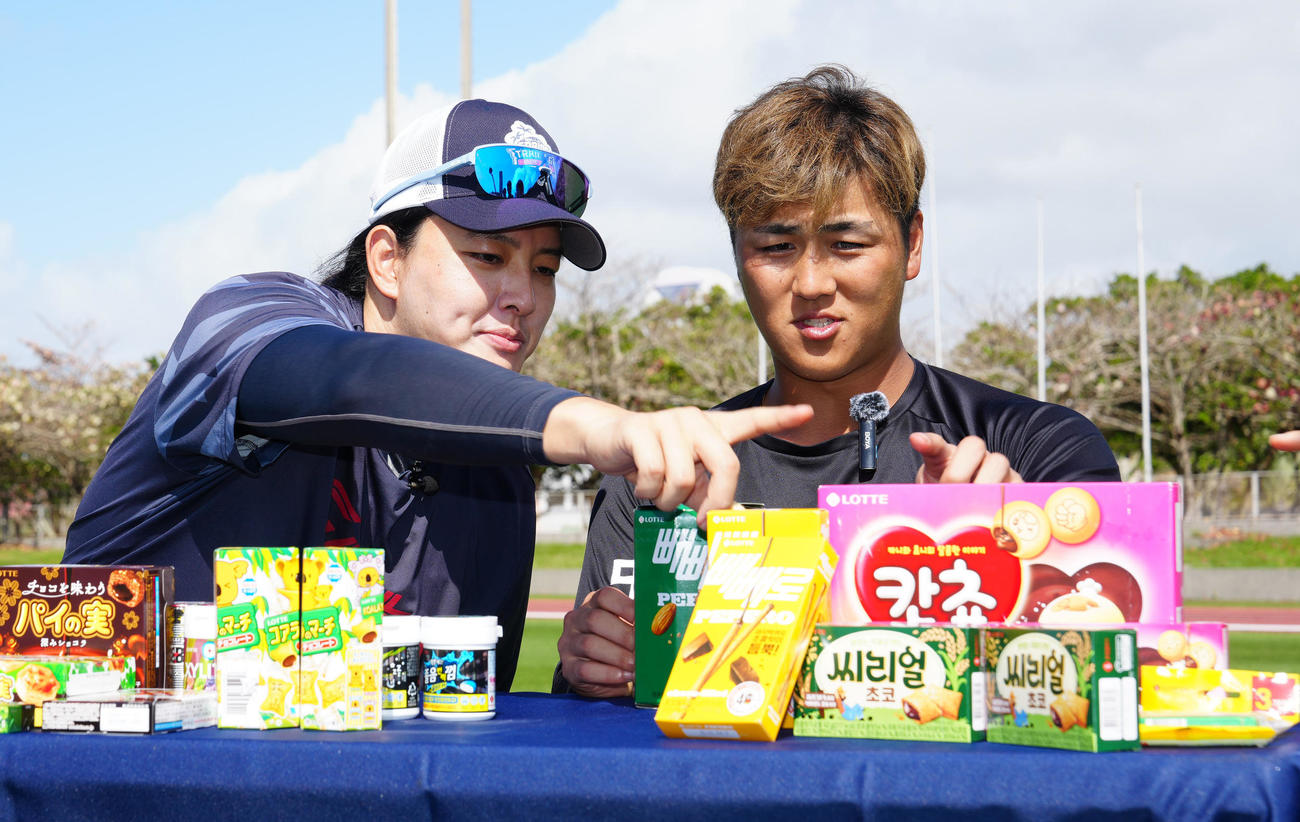 お菓子を食べ比べするロッテ山口（右）と韓国ロッテの金元中（撮影・江口和貴）