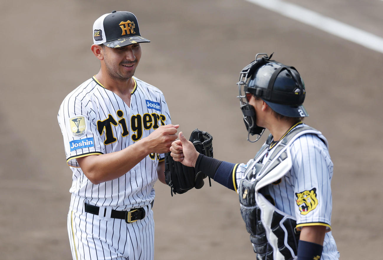 打撃投手を務めた阪神ゲラ（左）は、受けた梅野とグータッチ（撮影・前田充）
