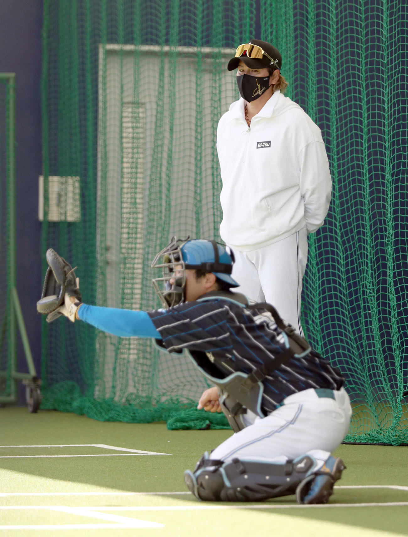 ブルペンで日本ハム上原健太の球を受ける郡司を見つめる新庄監督（右後方）（撮影・佐藤翔太）