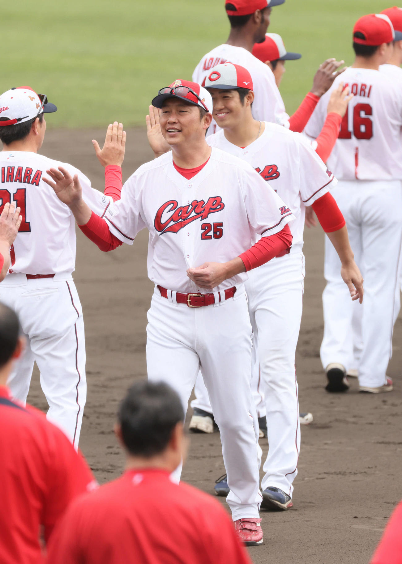 沖縄キャンプ終了で、ナインらとハイタッチする広島新井監督。右は高木（撮影・加藤孝規）
