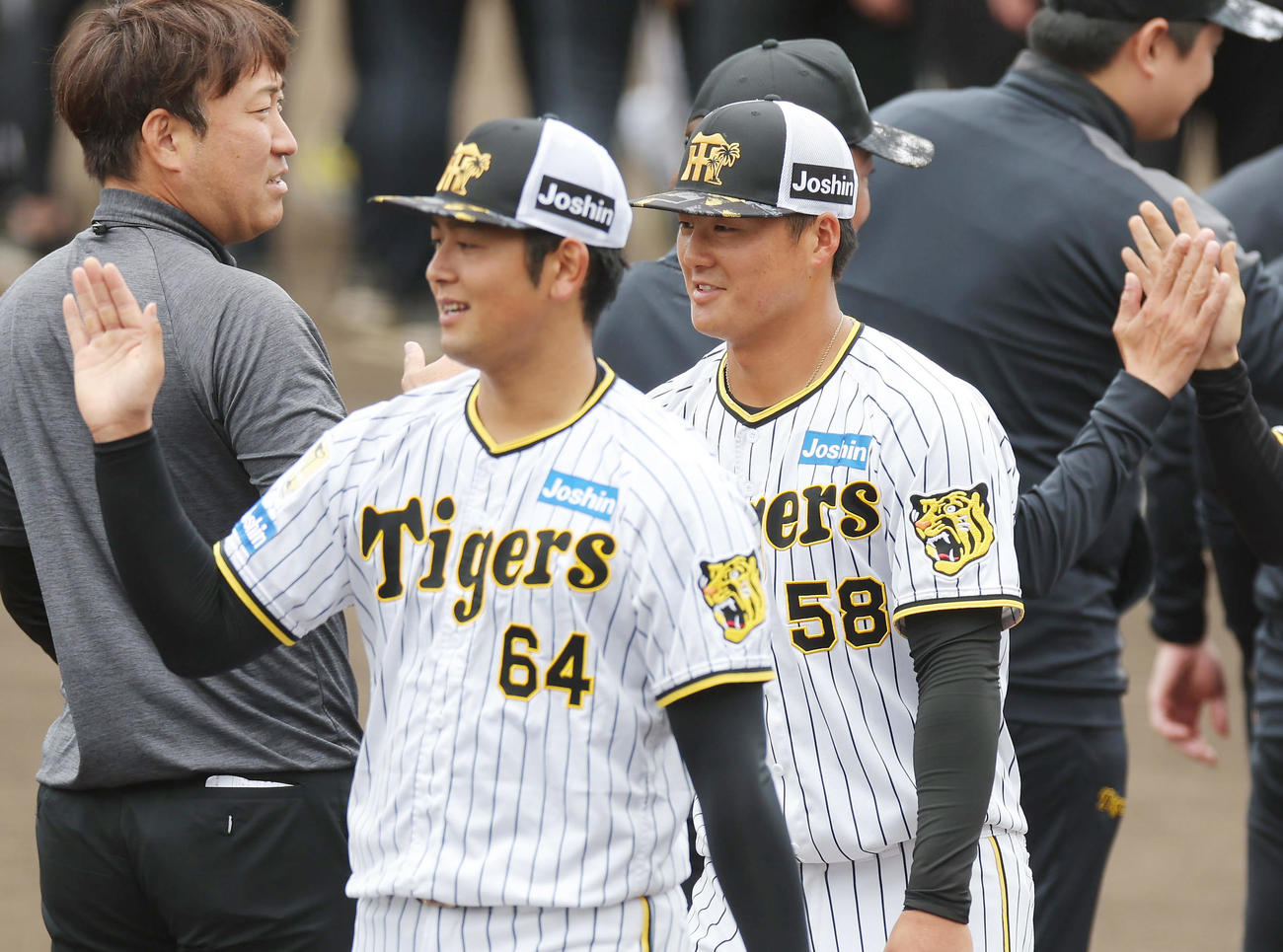 春季キャンプを打ち上げ、スタッフらとハイタッチを交わす阪神岡留（手前左）と前川（同右）（撮影・前田充）
